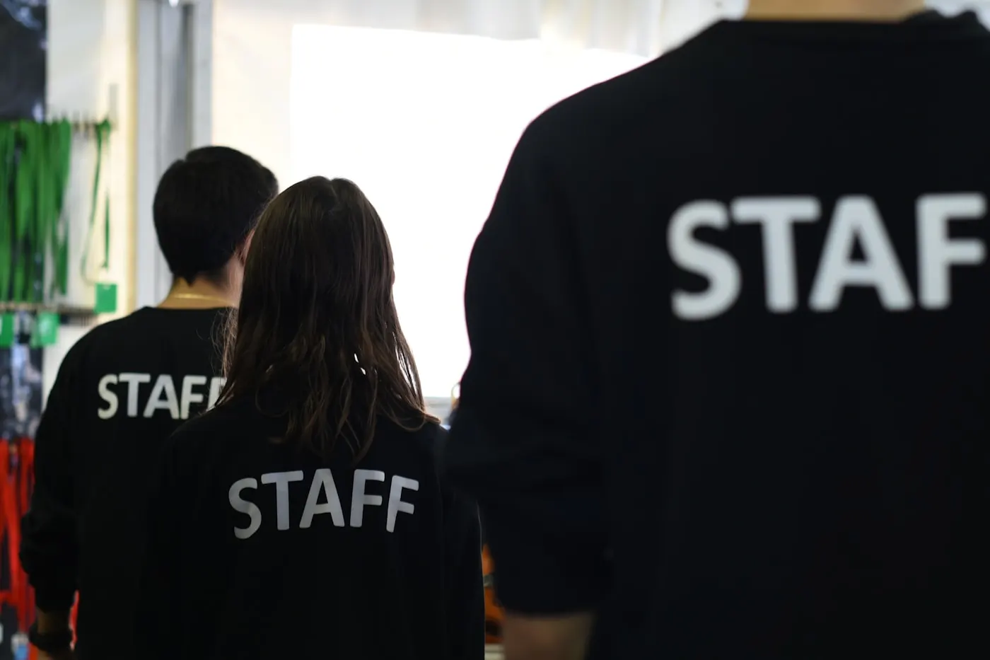 Personal de un evento, de espaldas, con chaquetas identificadas como «staff».