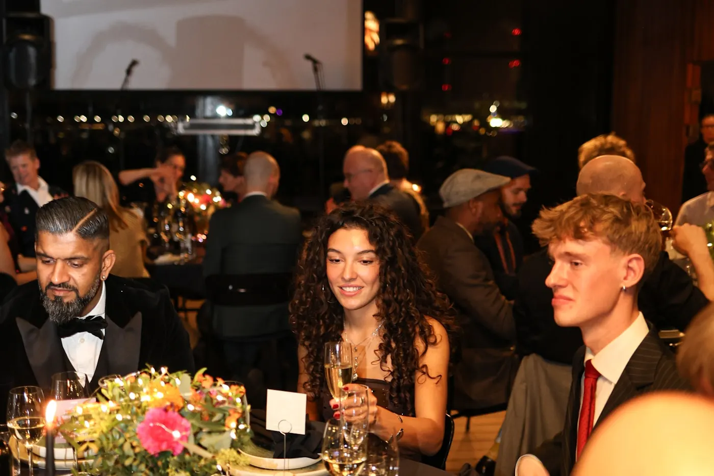 Cena de gala con invitados en mesas decoradas.